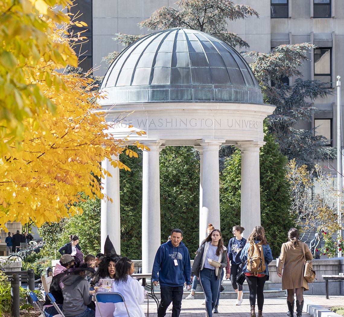 tempietto on GW campus with a yellow-leaved tree in the foreground and students walking by