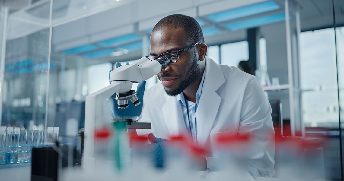 Researcher in a lab looking through a microscope