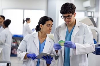Two medical laboratory scientists examine a sample in a lab.