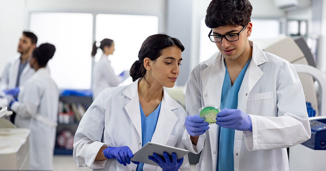 Two medical laboratory scientists examine a sample in a lab.
