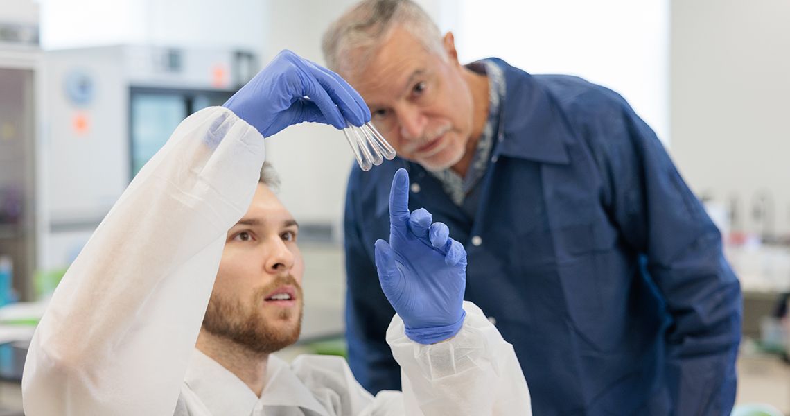 Professor examining vials with student in biomedical laboratory science program.]