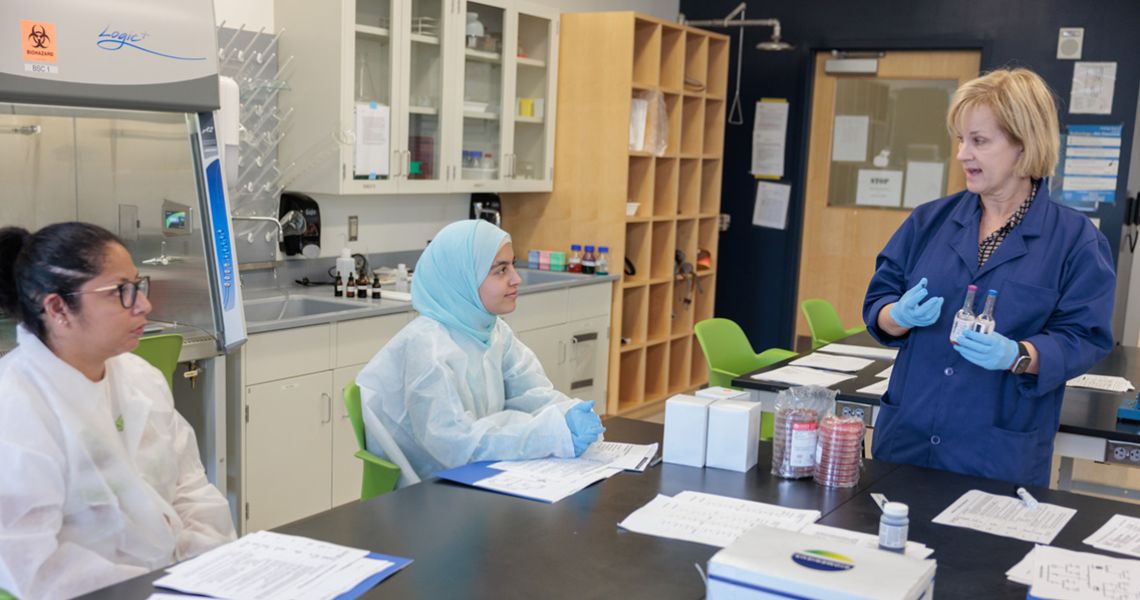 Clinical laboratory manager meets with research colegues in a lab setting.