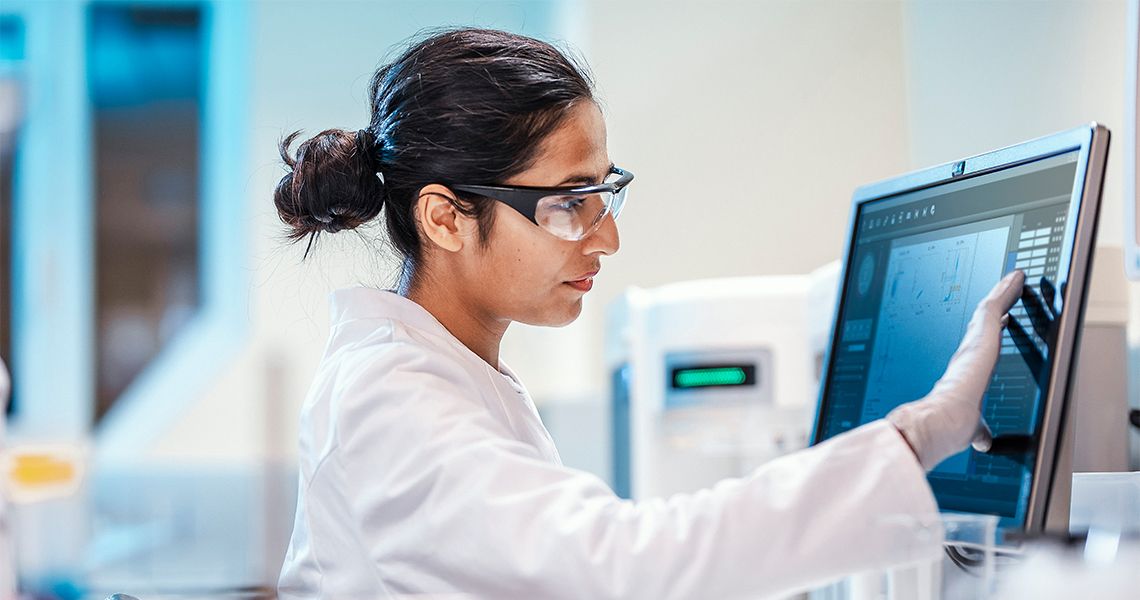 Health care professional reviewing biomedical informatics data on a screen.