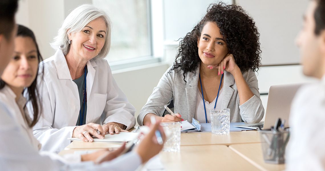 People in business attire and doctor's coats in a meeting