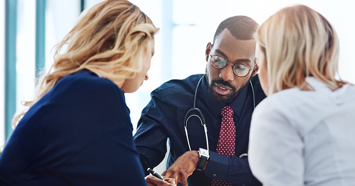 people in suits and stethoscopes having a meeting and writing things on a paper