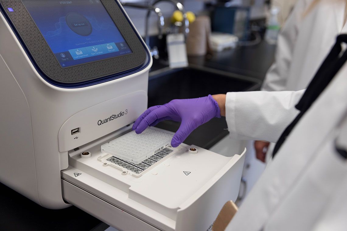 A lab worker putting a sample tray into a machine