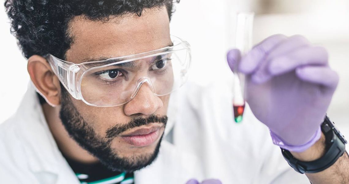 A researcher looks at a test tube