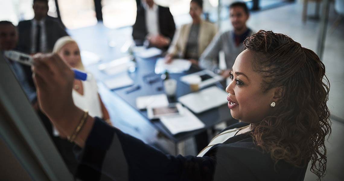 A woman presenting to a room of colleagues