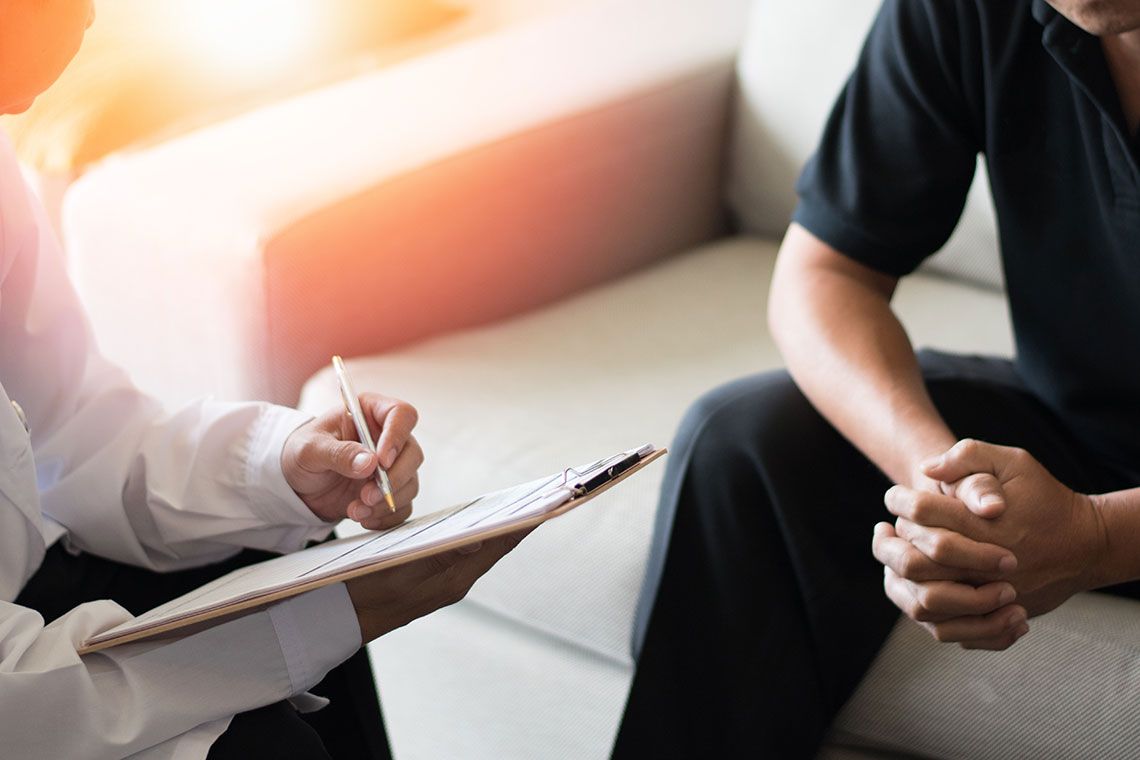 A doctor writing on a clipboard sitting with a patient