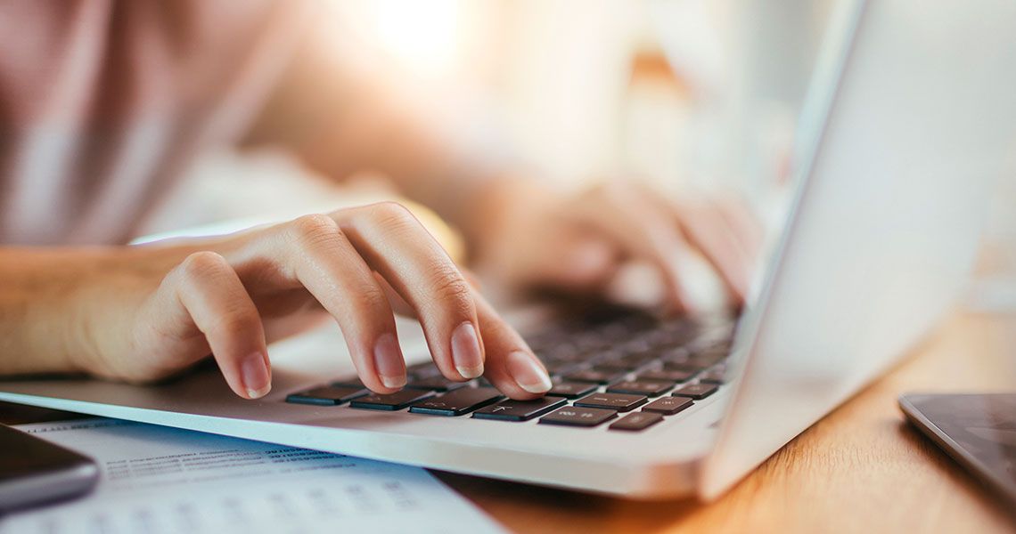 A person's hands typing on a laptop