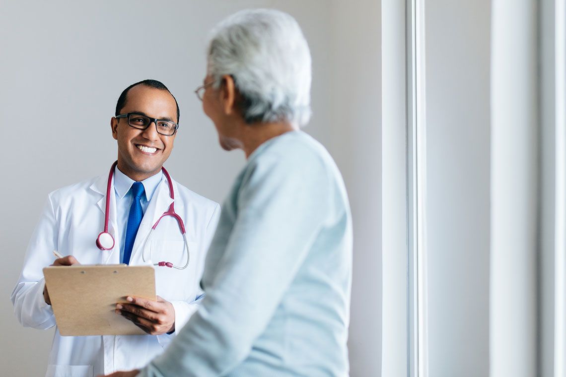 A doctor holding a clipboard and smiling at their patient