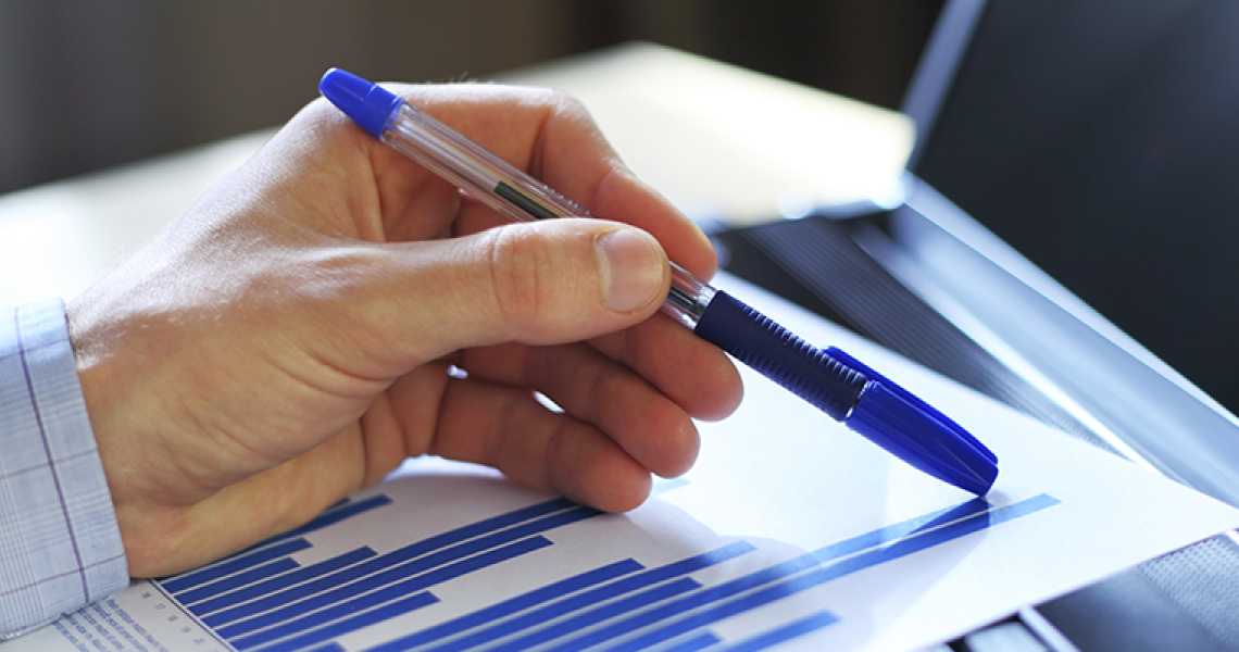 close up of hand holding a pen on a graph