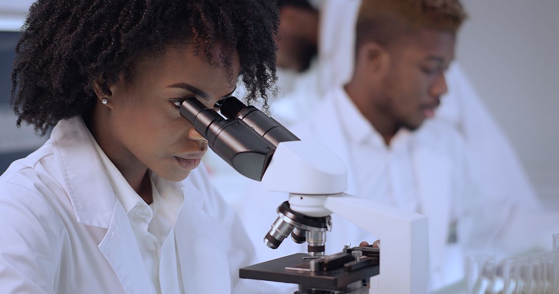 A female researcher looks through a microscope