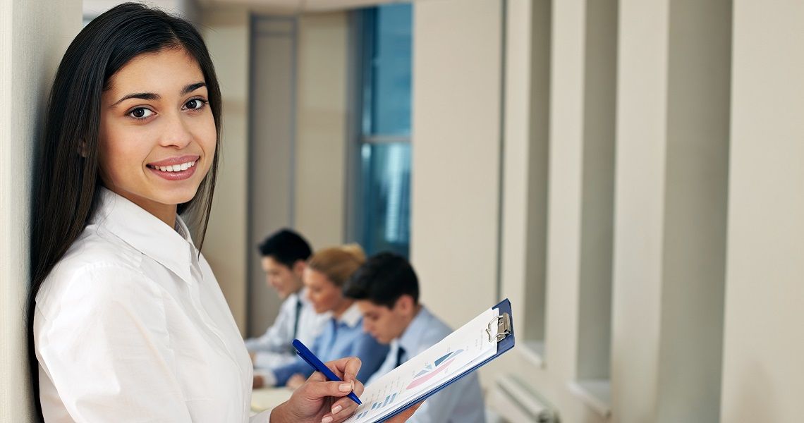 A woman looks up from a clipboard