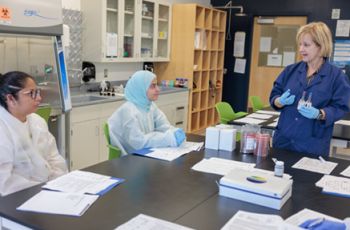 Clinical laboratory manager meets with research colegues in a lab setting.