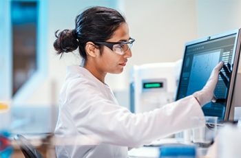 Health care professional reviewing biomedical informatics data on a screen.